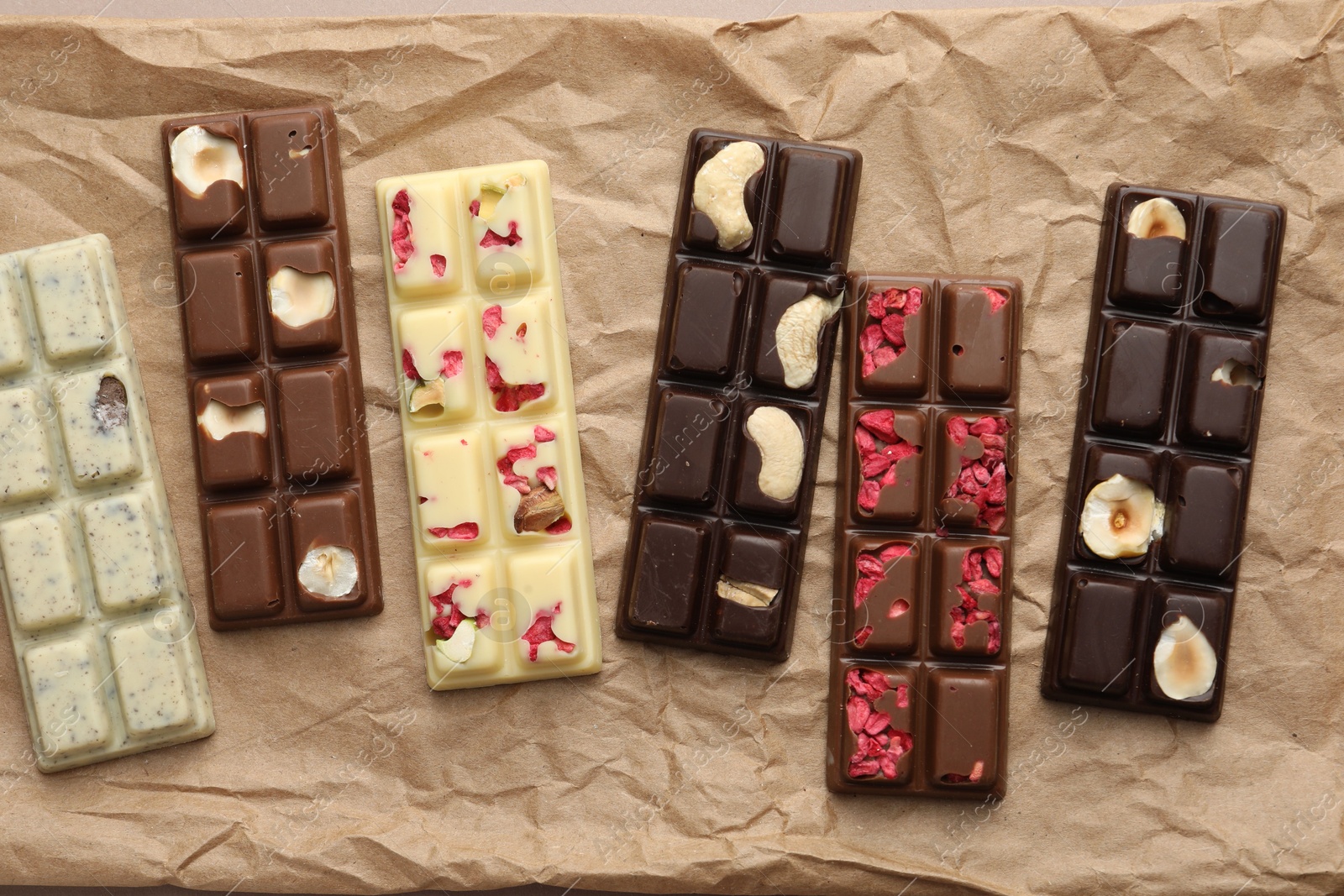 Photo of Different tasty chocolate bars on crumpled parchment, top view