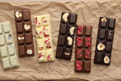 Photo of Different tasty chocolate bars on crumpled parchment, top view