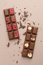 Photo of Tasty chocolate bars and crumbs on beige background, flat lay