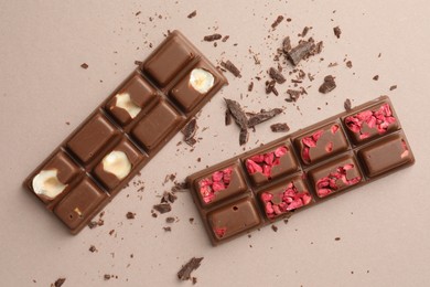 Photo of Tasty chocolate bars and crumbs on beige background, flat lay