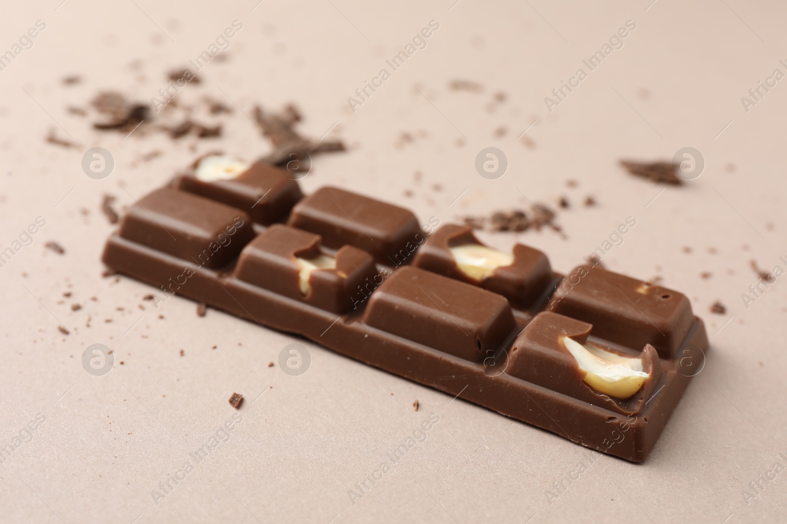 Photo of Tasty chocolate bar and crumbs on beige background, closeup