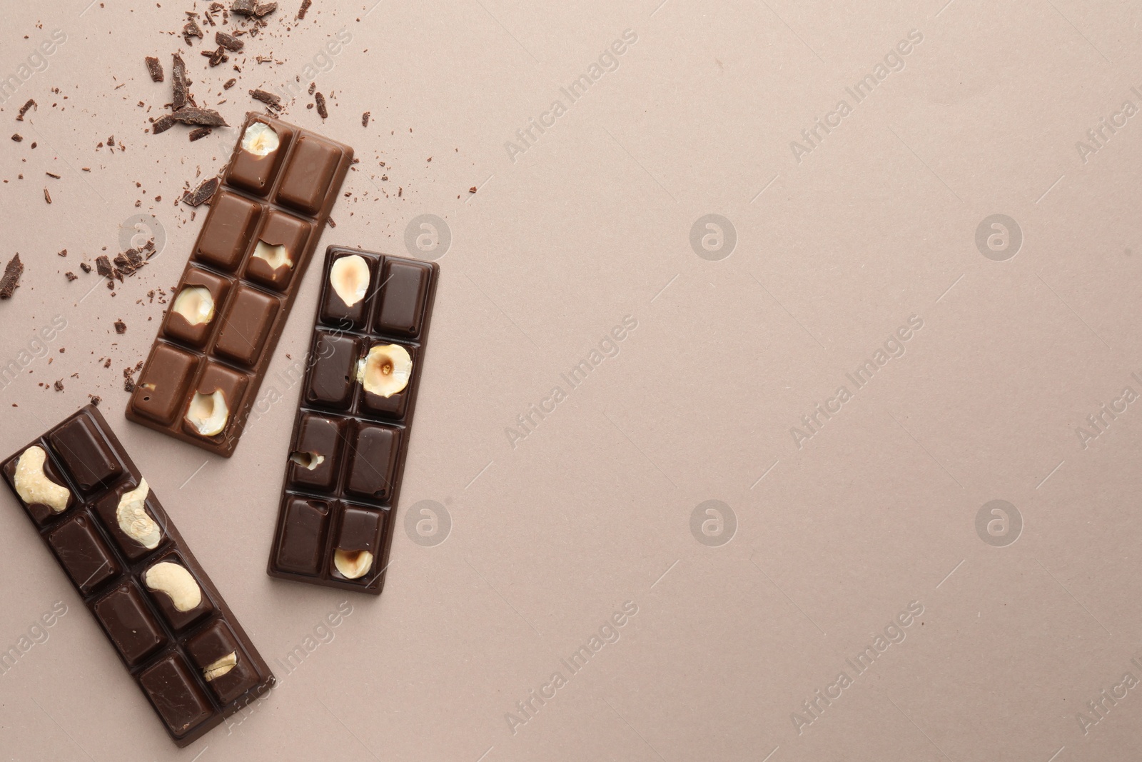 Photo of Tasty chocolate bars and crumbs on beige background, flat lay. Space for text