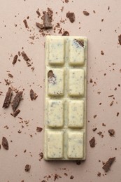 Photo of Tasty chocolate bar and crumbs on beige background, top view