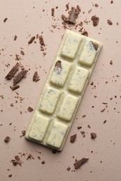 Photo of Tasty chocolate bar and crumbs on beige background, top view