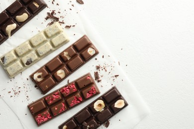 Photo of Tasty chocolate bars and crumbs on white textured background, flat lay. Space for text