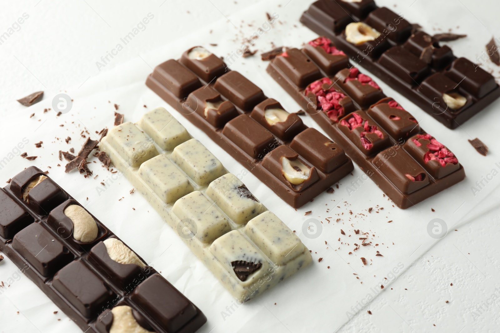 Photo of Tasty chocolate bars and crumbs on white background, closeup