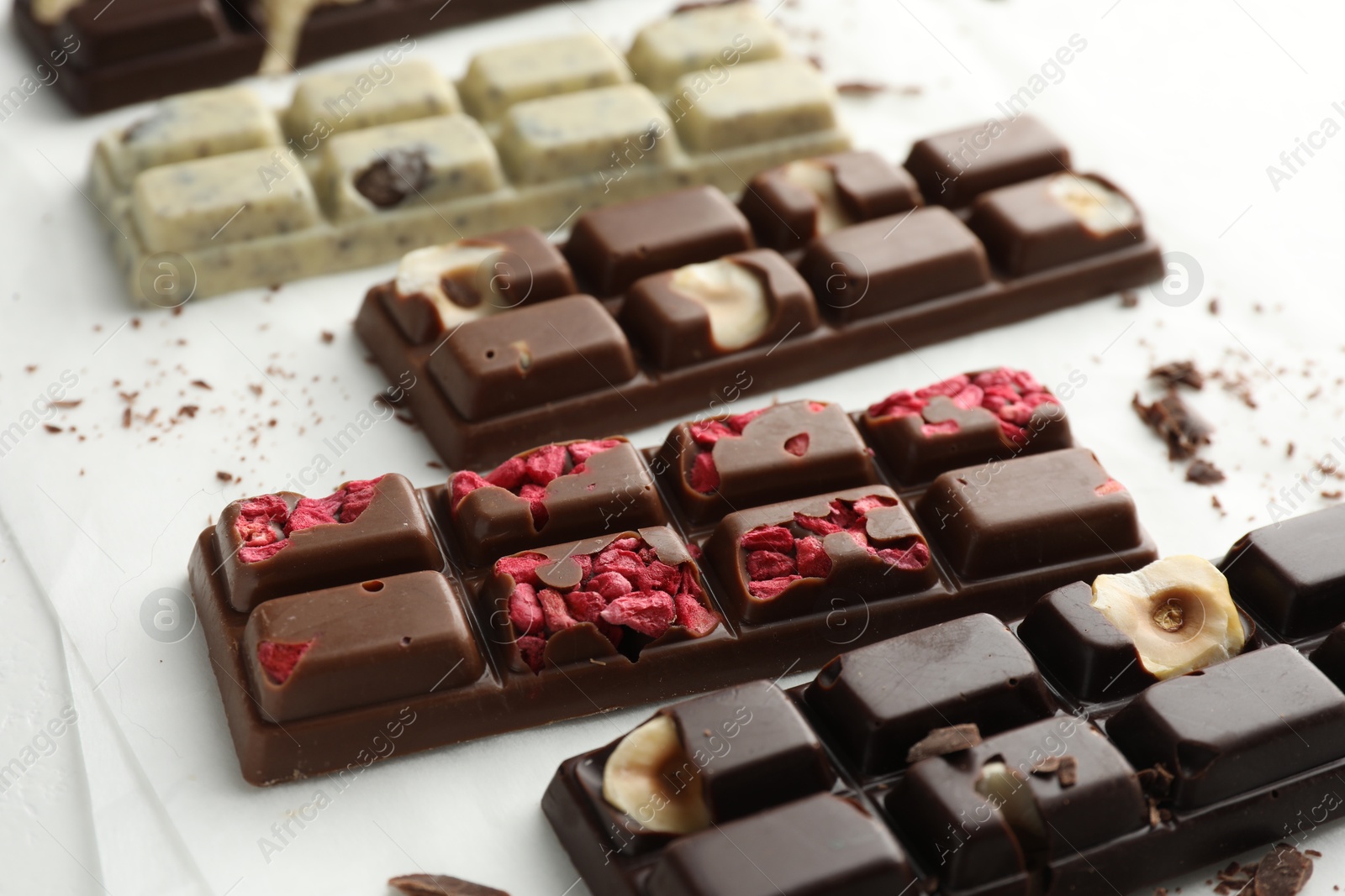 Photo of Tasty chocolate bars and crumbs on white background, closeup