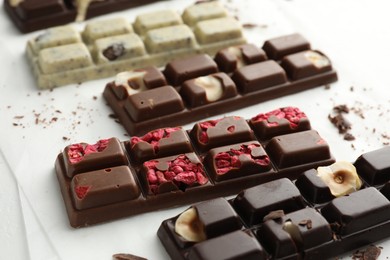 Photo of Tasty chocolate bars and crumbs on white background, closeup