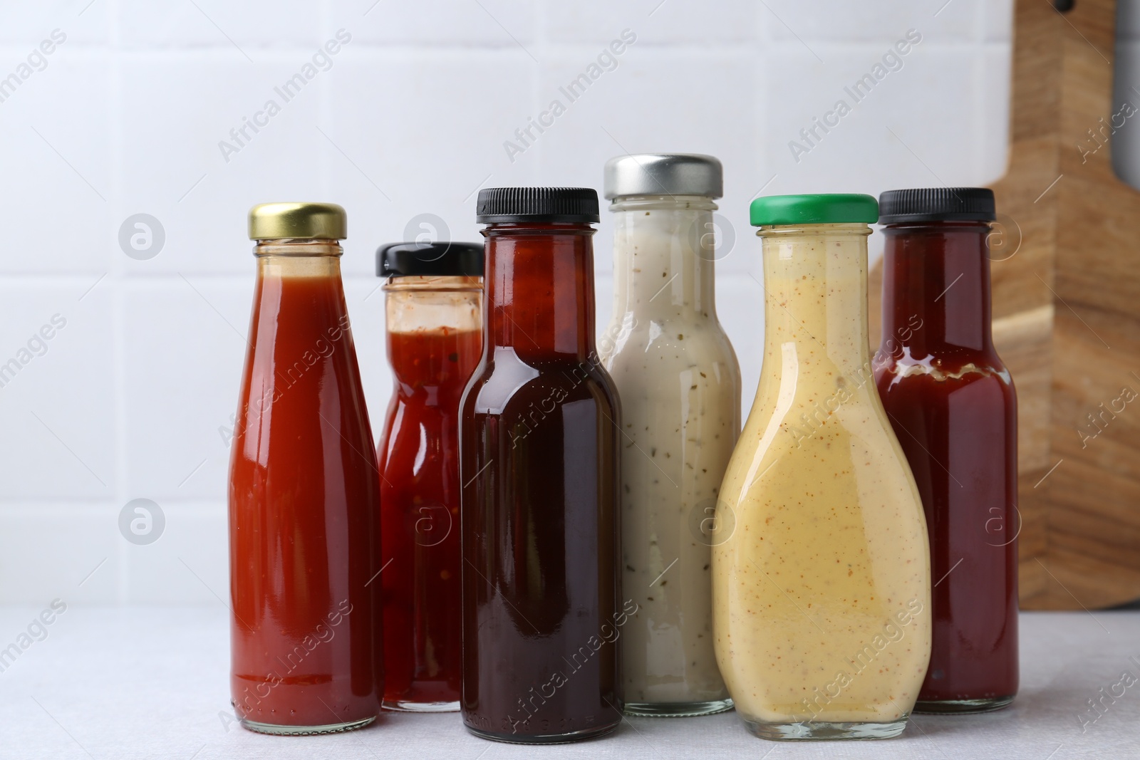 Photo of Tasty sauces in glass bottles on white table, closeup