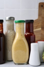 Photo of Tasty sauces in glass bottles on white table, closeup