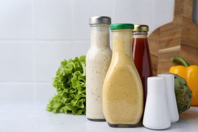 Photo of Tasty sauces in glass bottles on white table, closeup. Space for text