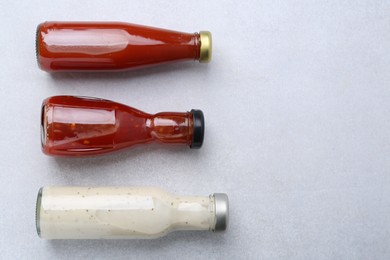 Photo of Tasty sauces in glass bottles on white table, flat lay. Space for text