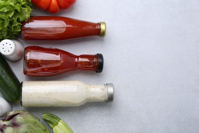 Photo of Tasty sauces in glass bottles and fresh products on white table, flat lay. Space for text