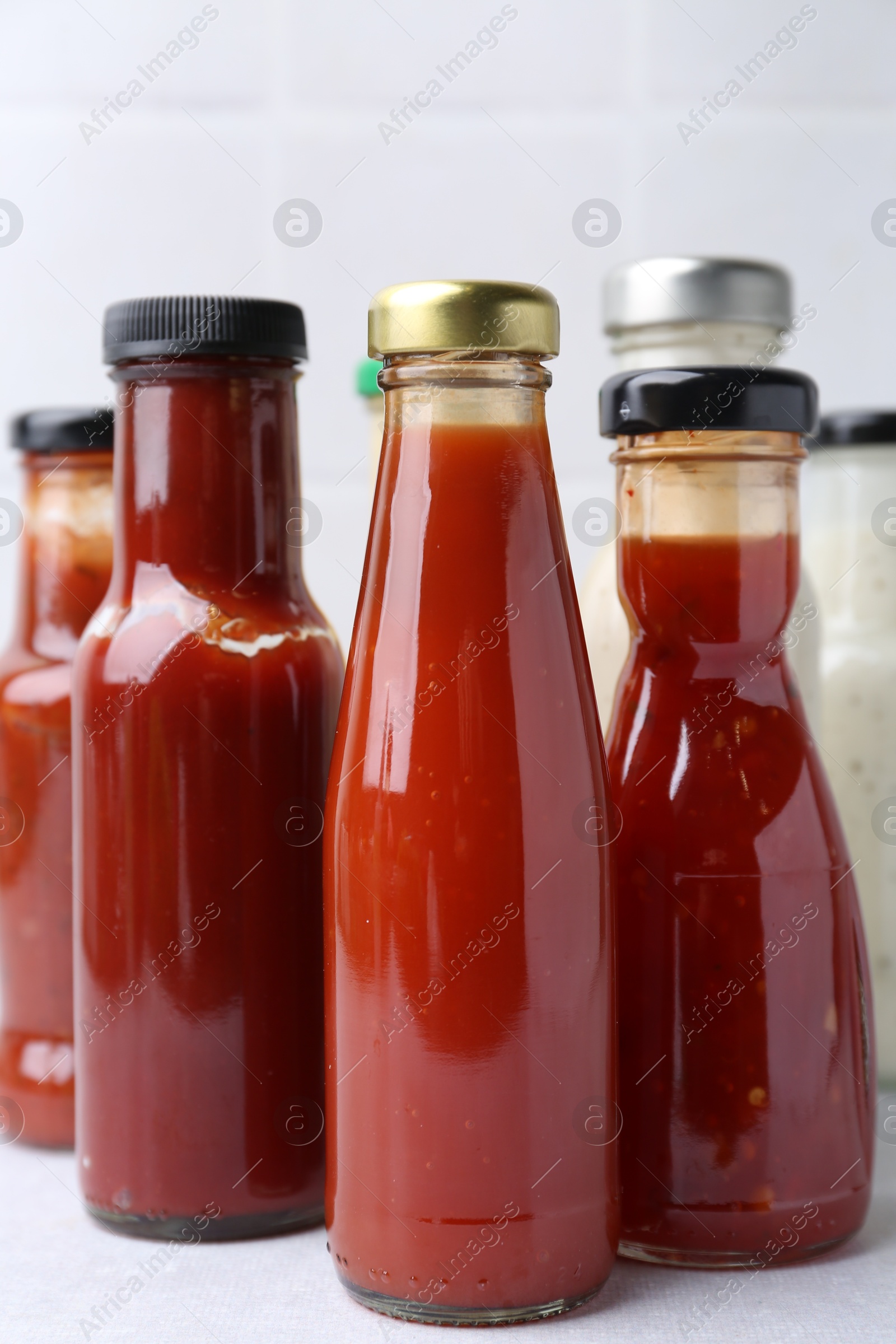 Photo of Tasty sauces in glass bottles on white table, closeup