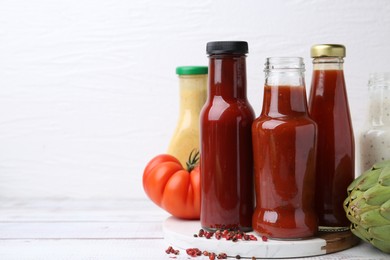 Photo of Tasty sauces in glass bottles and fresh products on wooden table, closeup. Space for text