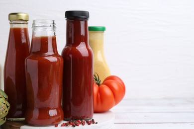 Tasty sauces in glass bottles and fresh products on wooden table, closeup. Space for text