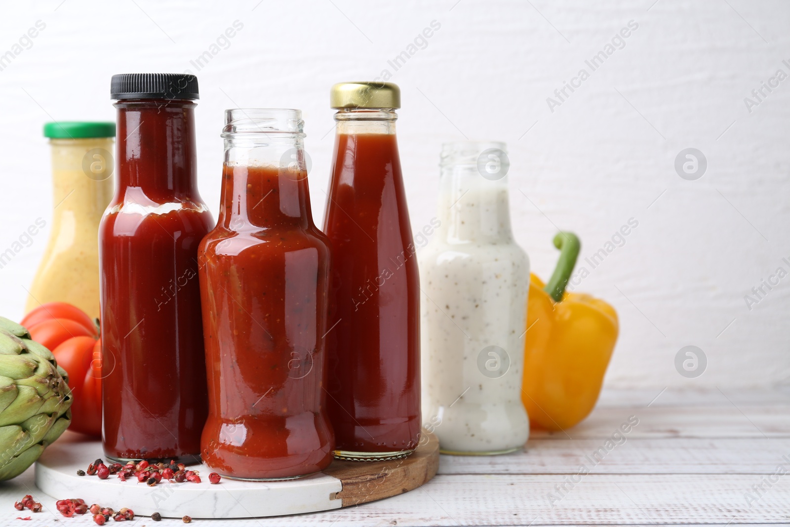 Photo of Tasty sauces in glass bottles and fresh products on wooden table, closeup. Space for text