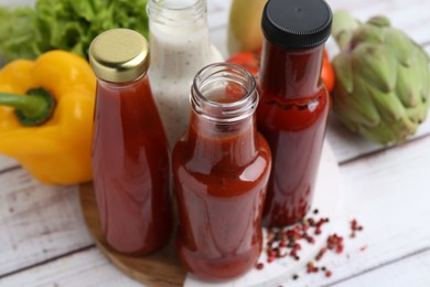 Photo of Tasty sauces in glass bottles and fresh products on white wooden table, closeup