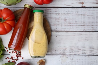 Photo of Tasty sauces in glass bottles and fresh products on white wooden table, flat lay. Space for text