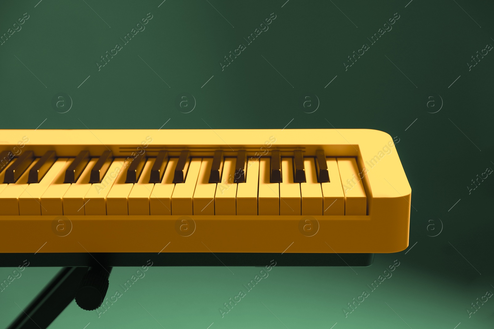 Image of Yellow synthesizer on green background, closeup. Electronic musical instrument