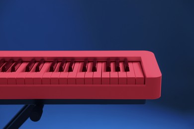 Image of Bright pink synthesizer on blue background, closeup. Electronic musical instrument