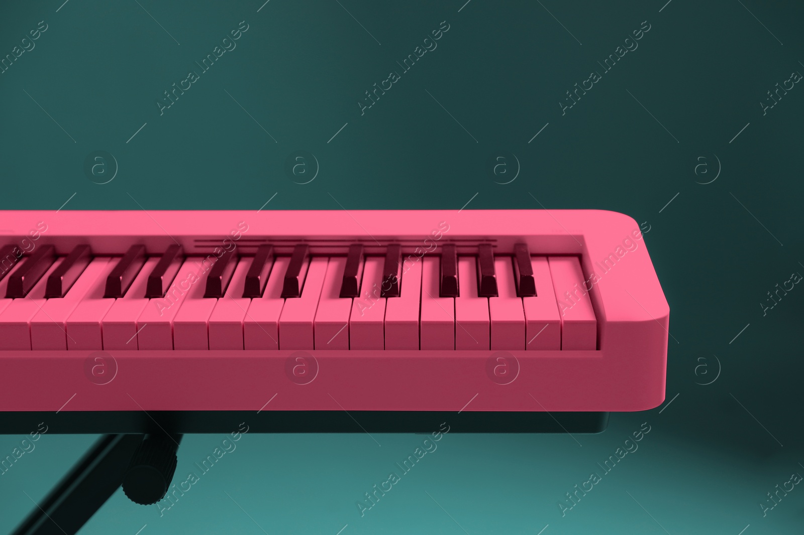 Image of Bright pink synthesizer on teal background, closeup. Electronic musical instrument