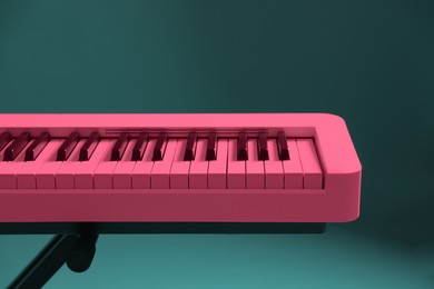 Image of Bright pink synthesizer on teal background, closeup. Electronic musical instrument