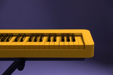 Image of Yellow synthesizer on purple background, closeup. Electronic musical instrument