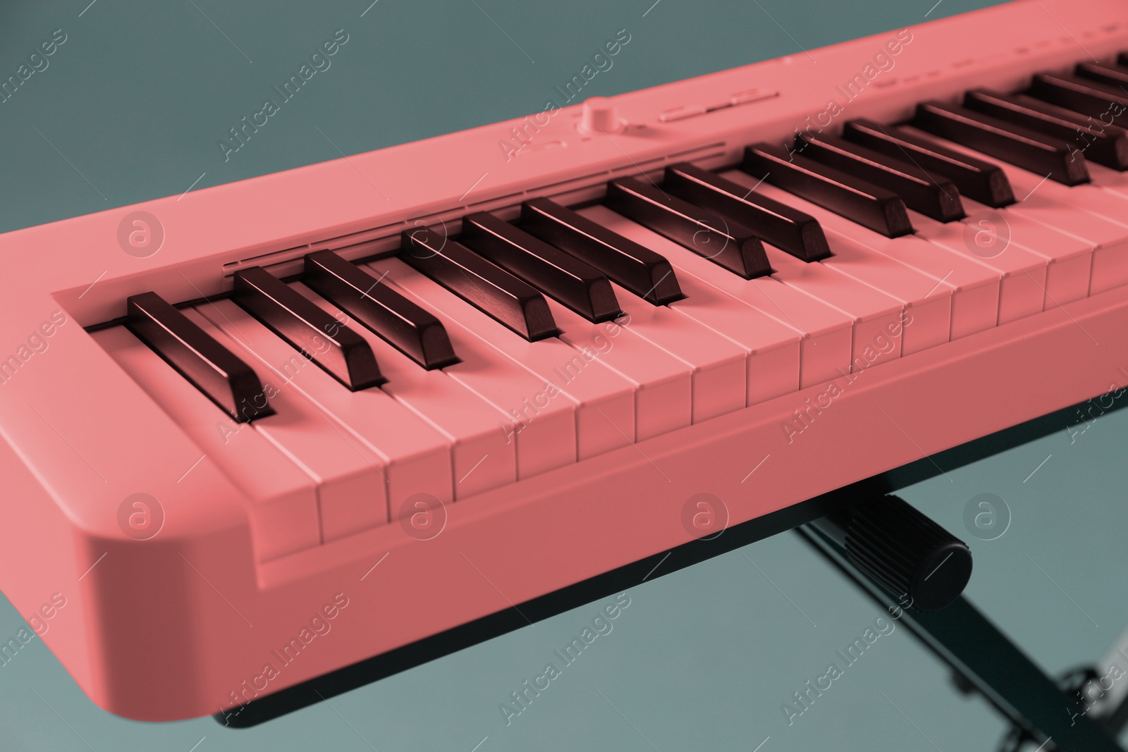 Image of Pink synthesizer on grey background, closeup. Electronic musical instrument