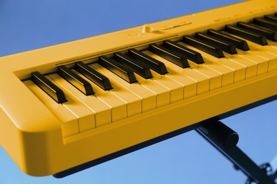 Image of Yellow synthesizer on light blue background, closeup. Electronic musical instrument