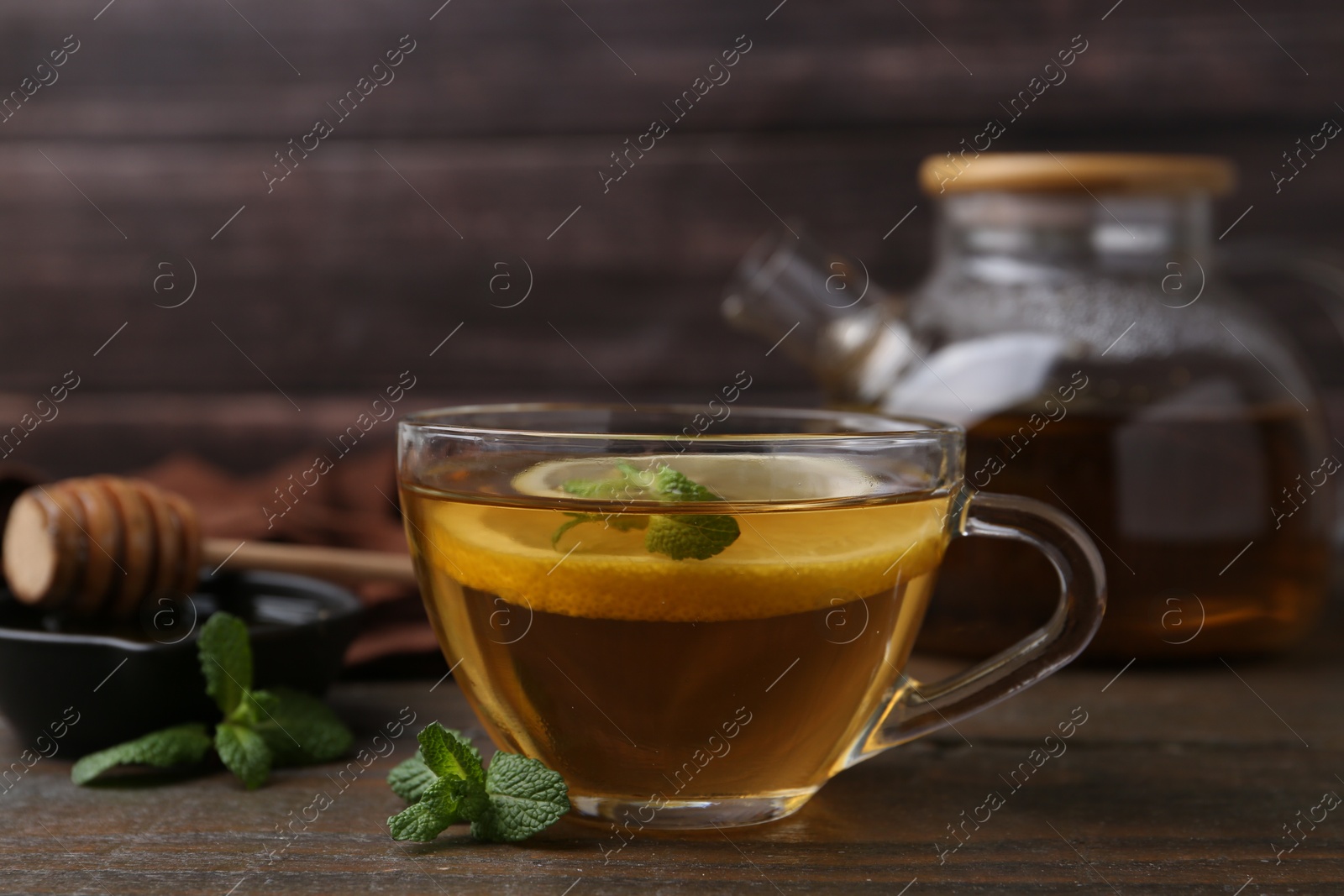 Photo of Tasty mint tea in cup, lemon and fresh leaves on wooden table, closeup