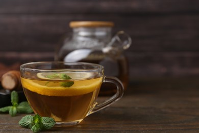 Photo of Tasty mint tea in cup, lemon and fresh leaves on wooden table, closeup. Space for text