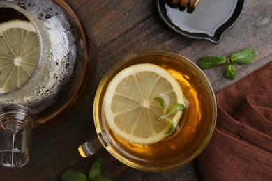 Photo of Tasty mint tea in cup, lemon and fresh leaves on wooden table, flat lay