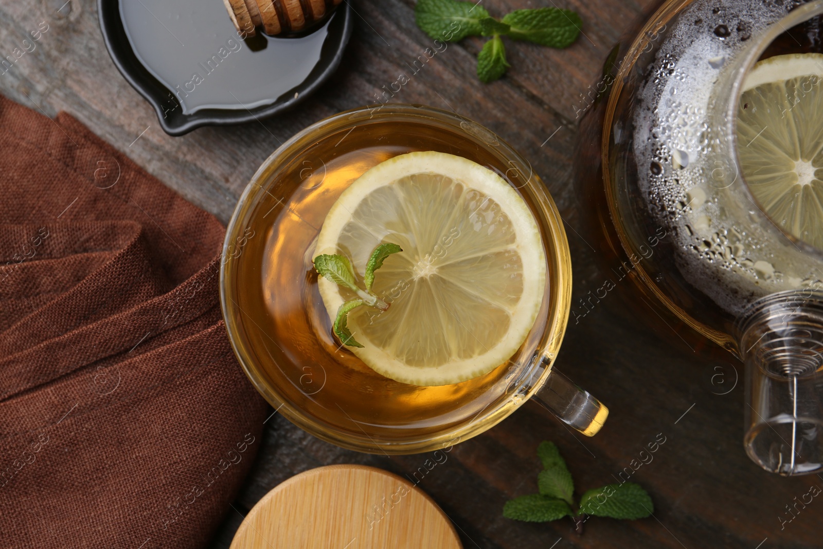 Photo of Tasty mint tea in cup, lemon and fresh leaves on wooden table, flat lay