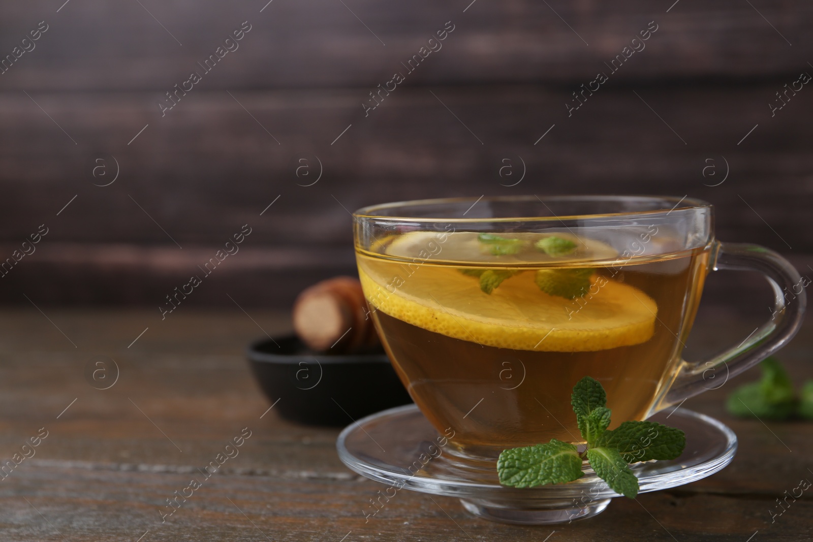 Photo of Tasty mint tea in cup, lemon and fresh leaves on wooden table, closeup. Space for text