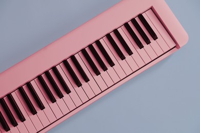 Image of Pink synthesizer on grey background, top view. Electronic musical instrument