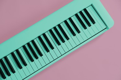 Image of Cyan color synthesizer on pink background, top view. Electronic musical instrument