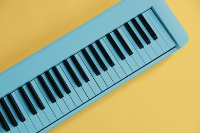 Image of Light blue synthesizer on yellow background, top view. Electronic musical instrument