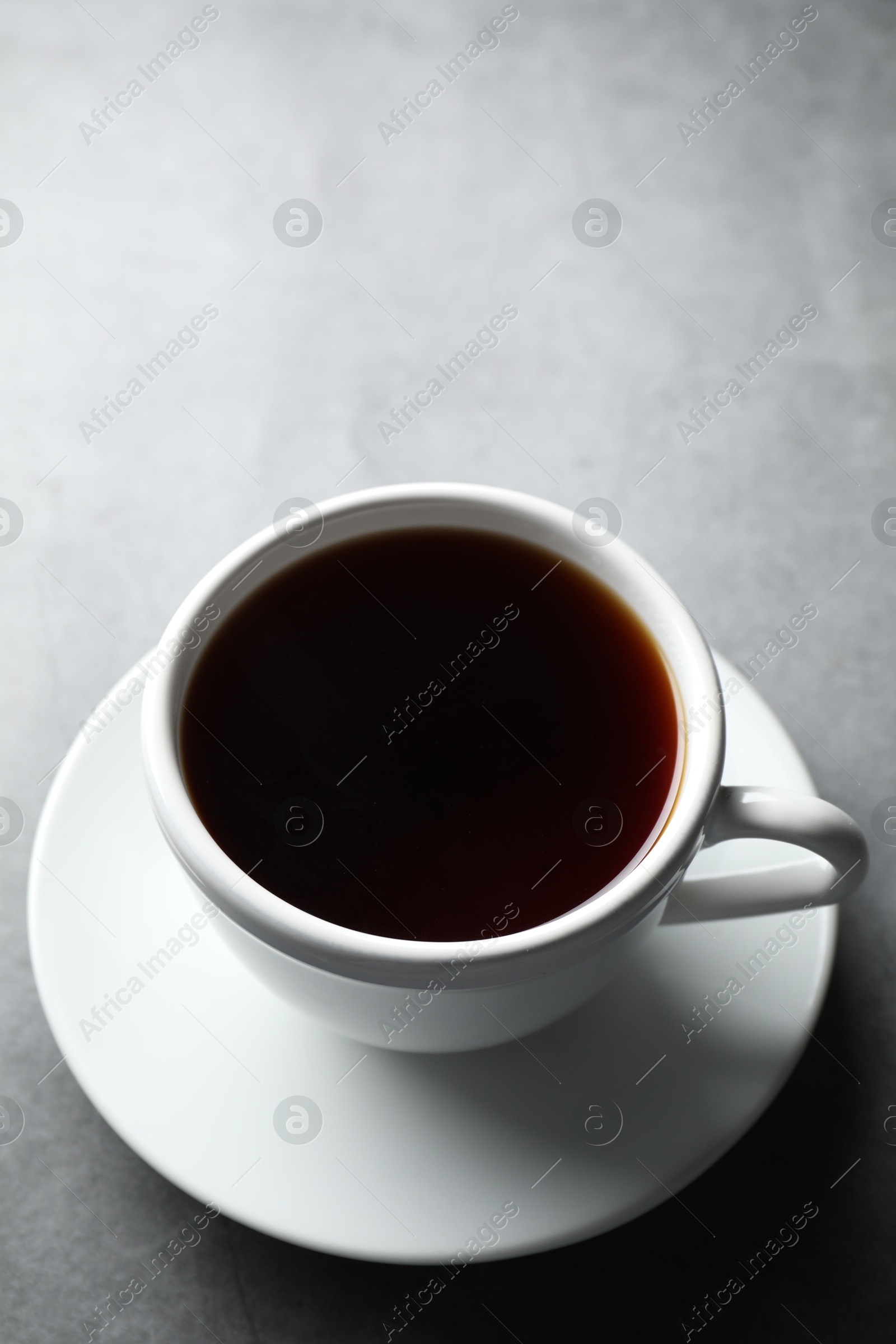 Photo of Refreshing black tea in cup on grey table