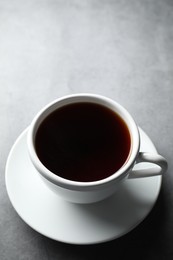 Photo of Refreshing black tea in cup on grey table