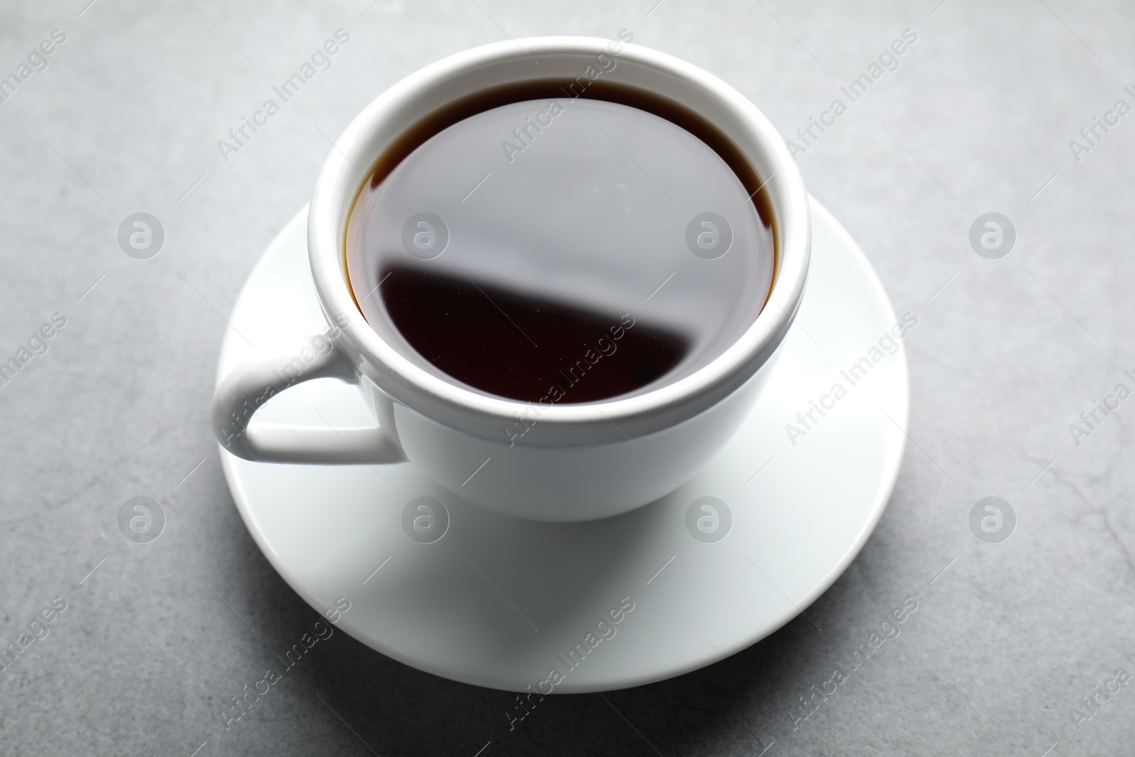 Photo of Refreshing black tea in cup on grey table, closeup