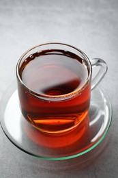 Refreshing black tea in cup on grey table, closeup