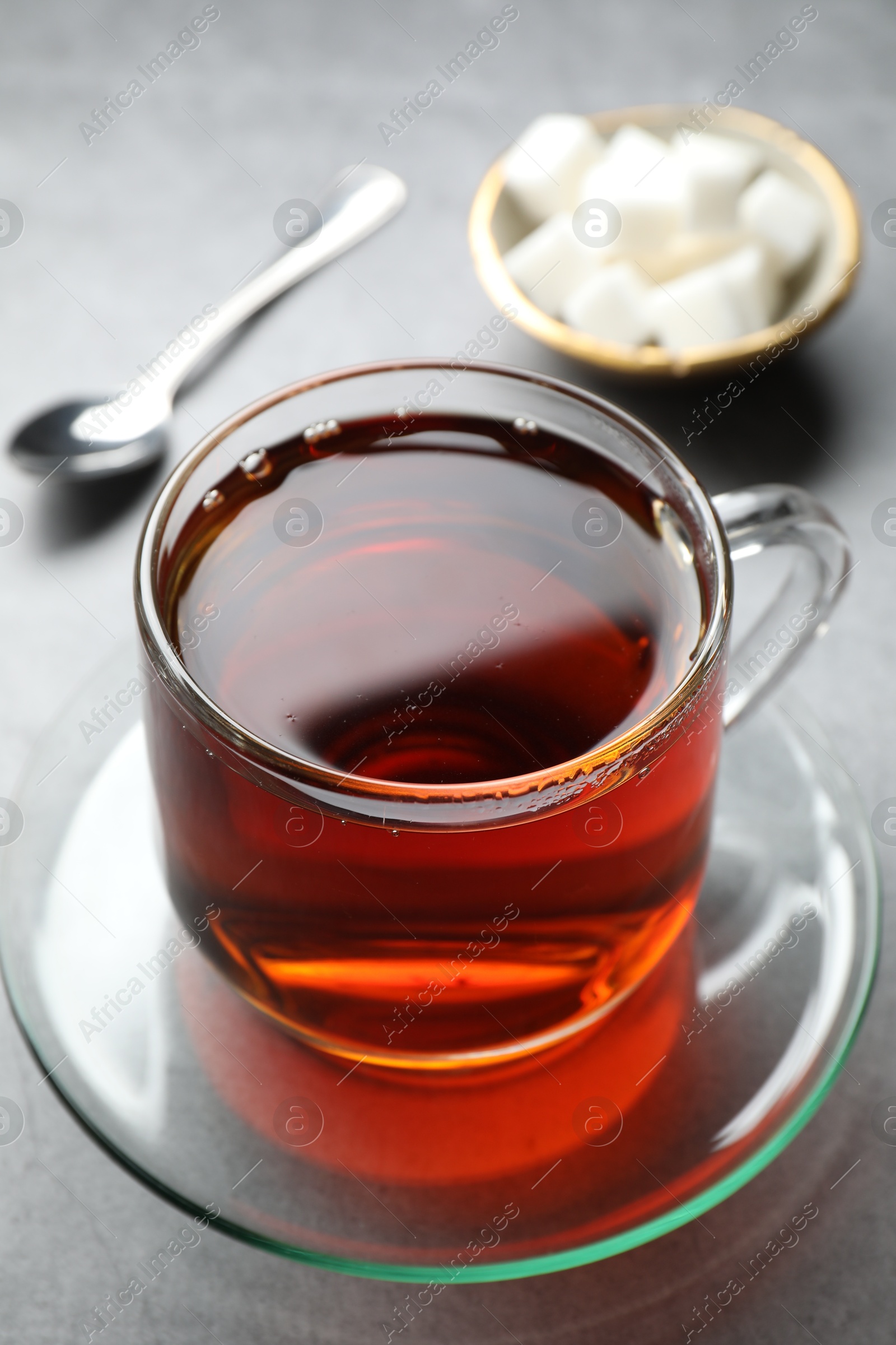 Photo of Refreshing black tea in cup on grey table, closeup