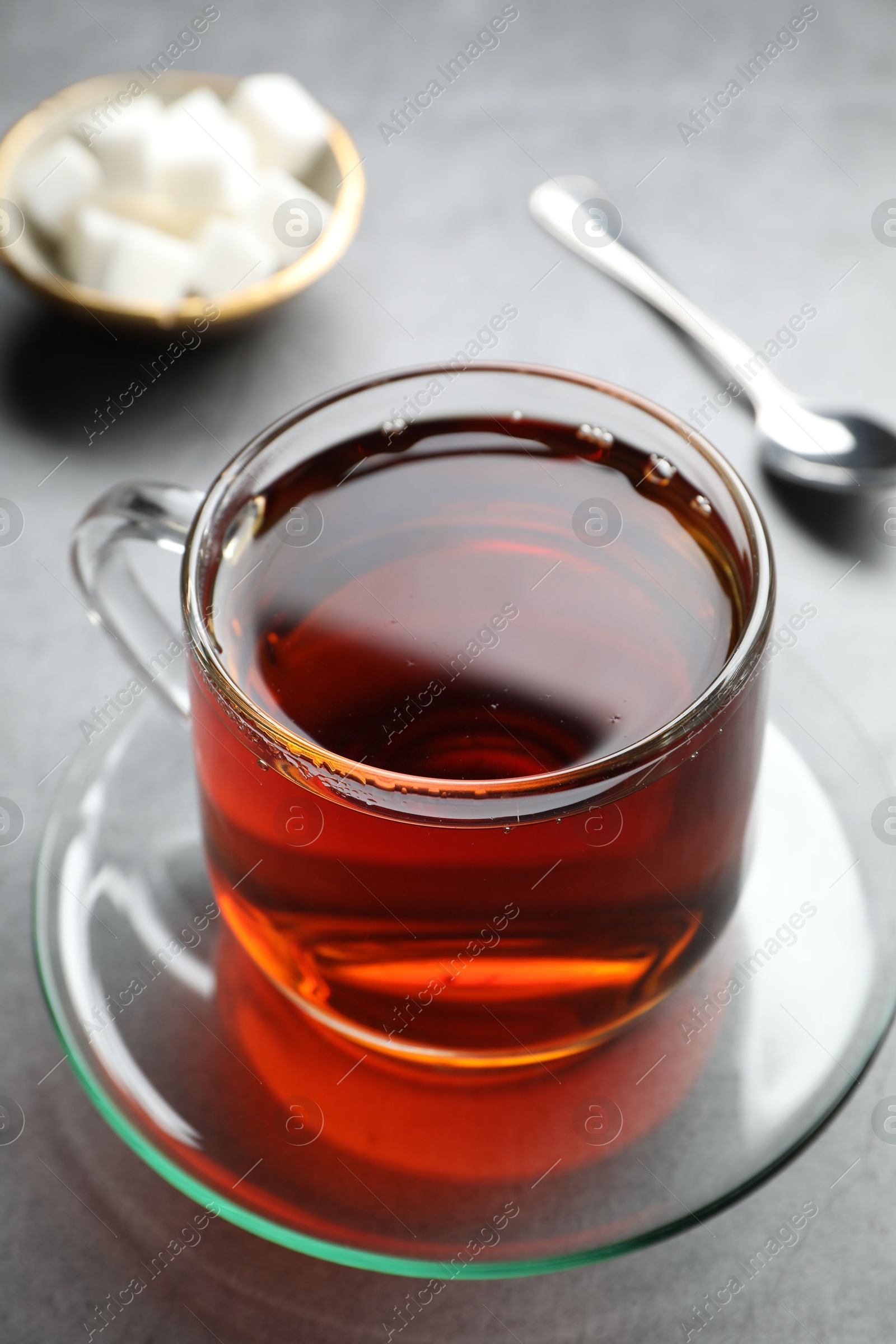 Photo of Refreshing black tea in cup on grey table, closeup