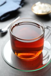 Photo of Refreshing black tea in cup on grey table, closeup