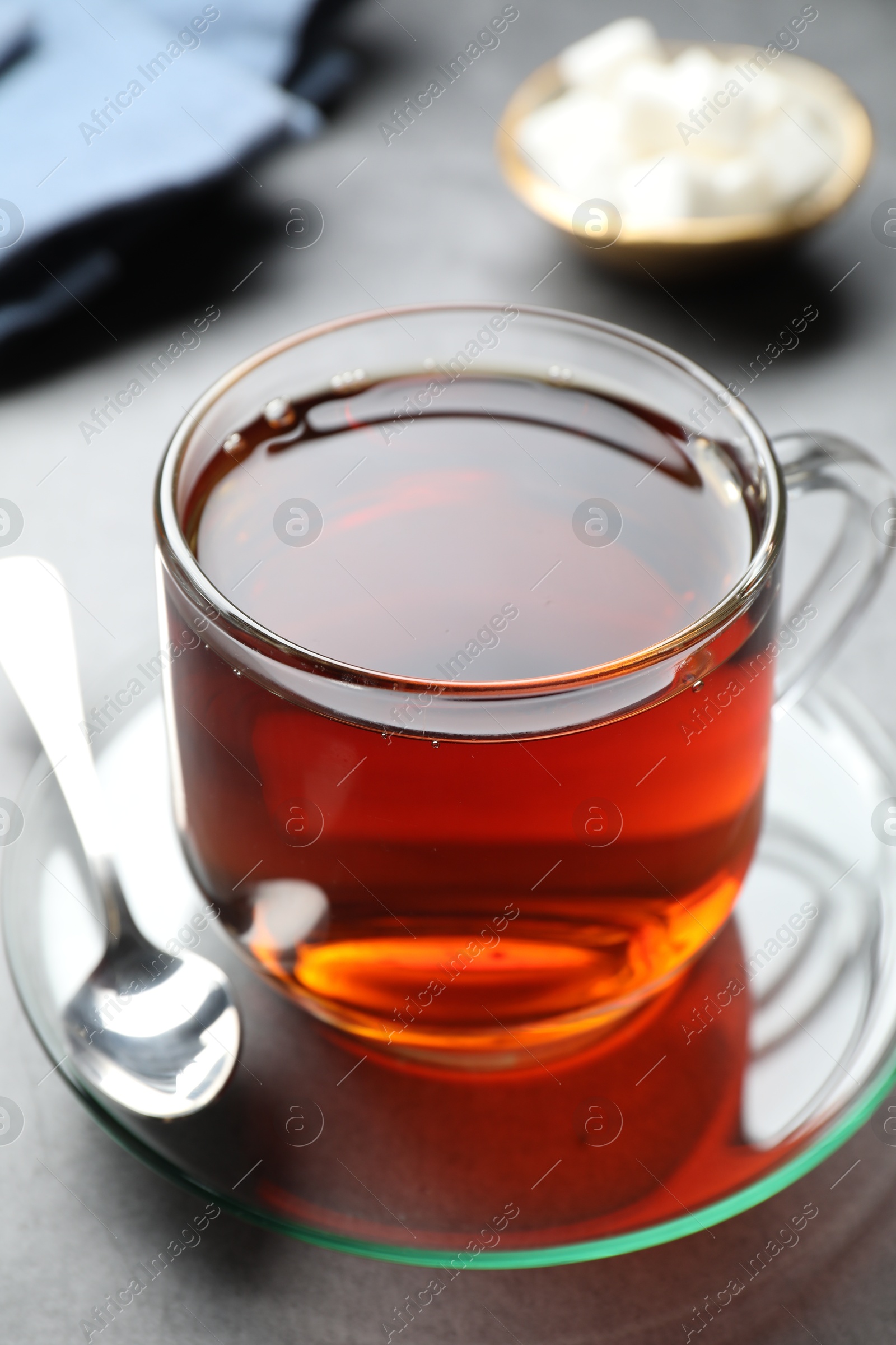 Photo of Refreshing black tea in cup on grey table, closeup