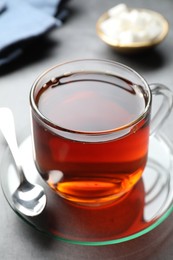 Photo of Refreshing black tea in cup on grey table, closeup