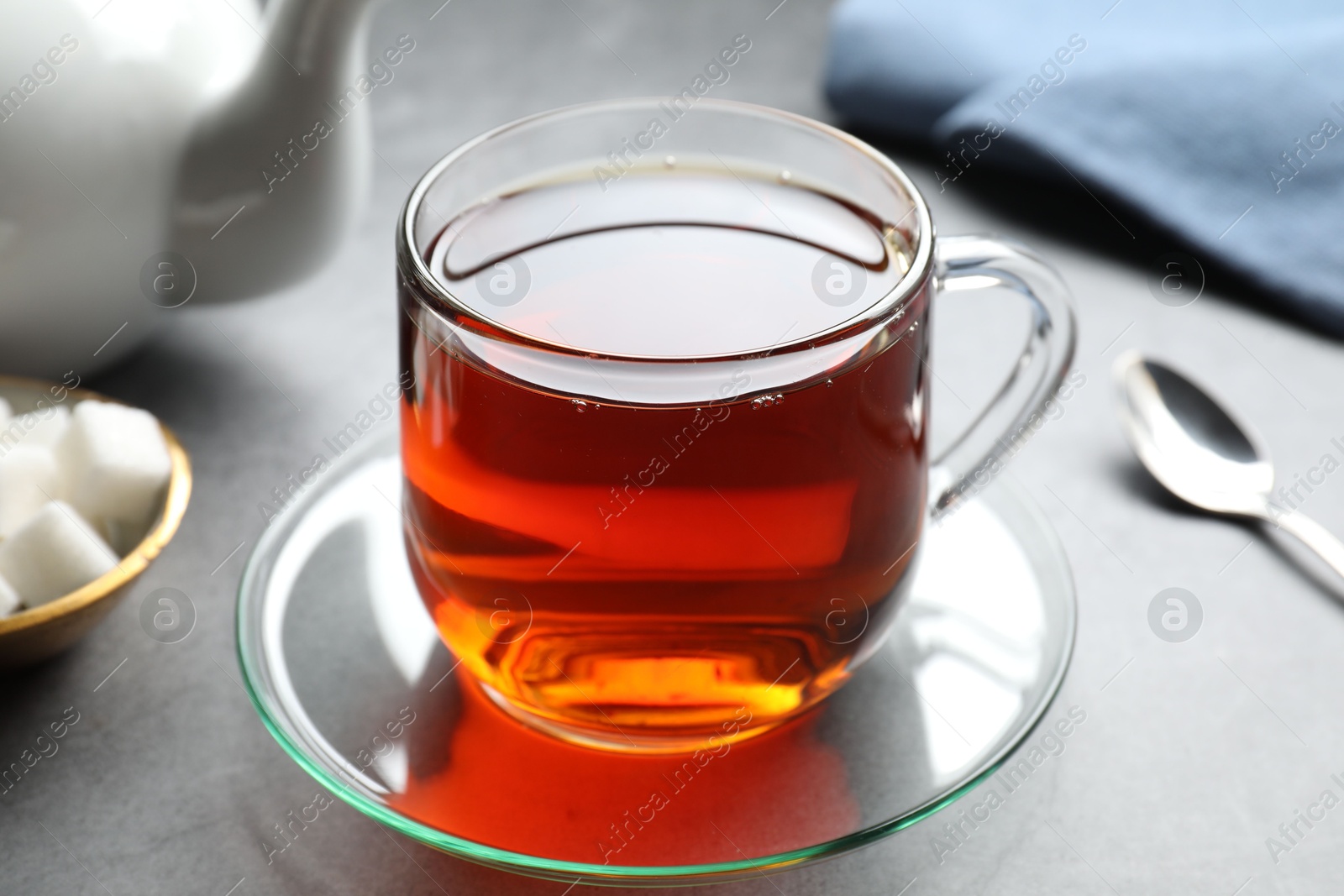 Photo of Refreshing black tea in cup on grey table, closeup