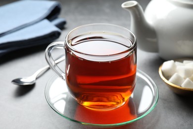 Photo of Refreshing black tea in cup on grey table, closeup