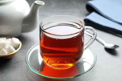 Photo of Refreshing black tea in cup on grey table, closeup